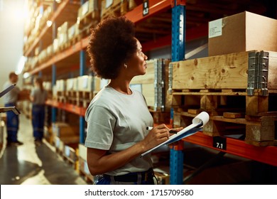 African American Worker Writing Inventory List While Checking Stock In Storage Room.