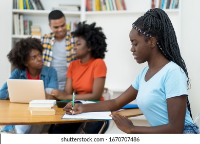 African american young adult with dreads and group of students at classroom of university