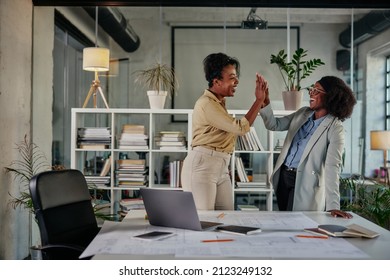 African american young adult two colleagues giving each other a high five at work - Powered by Shutterstock