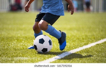 African American Young Boy Playing Soccer In A Stadium Pitch. Child Running With Soccer Ball Along The Field White Sideline. Junior Soccer Background