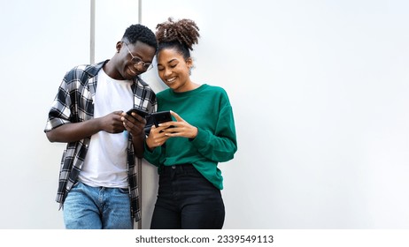 African American young couple looking smart phones together standing against white wall. Copy space. - Powered by Shutterstock