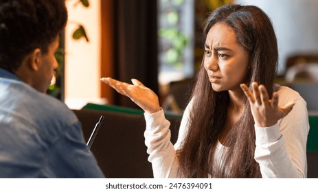 African American young girl with long hair appears frustrated while having an intense discussion with a guy. She is gesturing with her hands, highlighting her apparent confusion or disagreement - Powered by Shutterstock