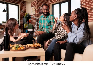 African american young man adult seriously speaking, discussing, talking, chatting to culturally diverse group adult people at living room home reunion. Multicultural friends drinking wine. - Powered by Shutterstock