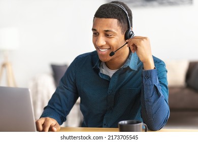 African american young man customer support call center operator or receptionist sitting at the workplace in a modern office consulting a client, uses a headset, smiles friendly - Shutterstock ID 2173705545
