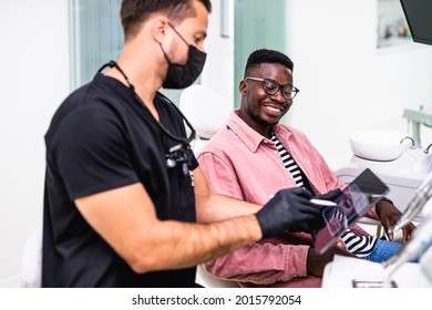 African American Young Man Having A Visit At The Dentist's. He Is Sitting On Chair At Dentist Office In Dental Clinic.