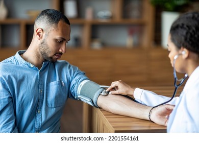 African American Young Man Having Regular Checkup At General Practitioner At Modern Clinic, Black Woman Doctor Checking Heart Rate For Male Patient Suffering From Hypertension, Copy Space