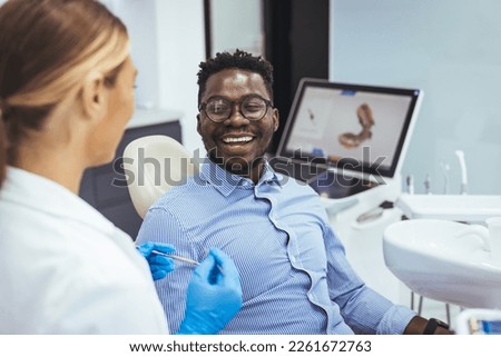 African American young man having a visit at the dentist's. He is sitting on chair at dentist office in dental clinic.. Happy dentist and patient in dentist's office. My dentist is the best! 