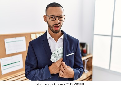 African American Young Man Hiding Dollars In Jacket Clueless And Confused Expression. Doubt Concept. 