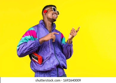 African American Young Man, In A Jacket In The Style Of The 90s, With A Retro Cassette Player, Hears Music, The Mood Of Dancing And Fun, Yellow And Purple Colors