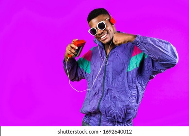 African American Young Man, In A Jacket In The Style Of The 90s, With A Retro Cassette Player, Hears Music, The Mood Of Dancing And Fun, Yellow And Purple Colors