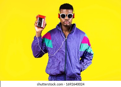 African American young man, in a jacket in the style of the 90s, with a retro cassette player, hears music, the mood of dancing and fun, yellow and purple colors