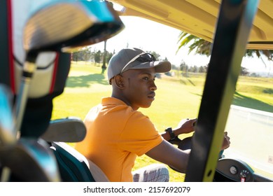 African American Young Man Wearing Cap And Sunglasses Looking Away While Driving Golf Cart. Transportation, Golf, Unaltered, Nature And Weekend Activities Concept.