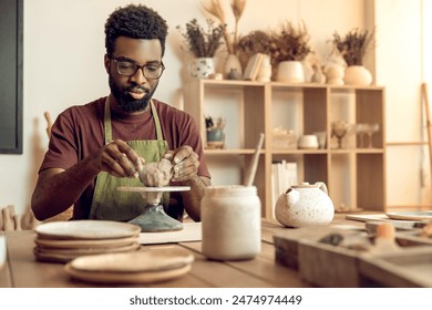 African american young man working with clay in pottery studio - Powered by Shutterstock