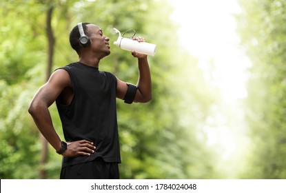 African american young sportsman drinking water, having break during exercising open air, copy space, side view