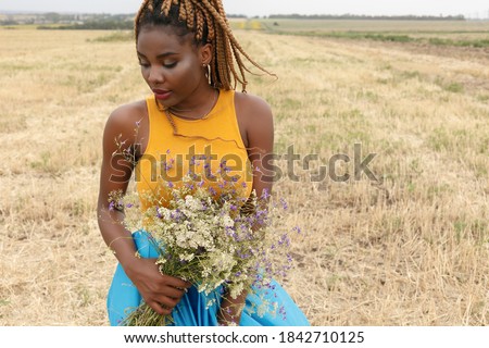 african american young woman having fun outdoors at sunset. laughing girl on field. bouquet of wild flowers. beautiful young african american 