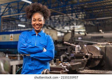 African American Young woman worker  in protective uniform operating machine at factory Industrial.People working in industry.Portrait of Female  Engineer looking camera  at work place. - Powered by Shutterstock