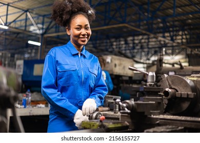 African American Young woman worker  in protective uniform operating machine at factory Industrial.People working in industry.Portrait of Female  Engineer looking camera  at work place. - Powered by Shutterstock