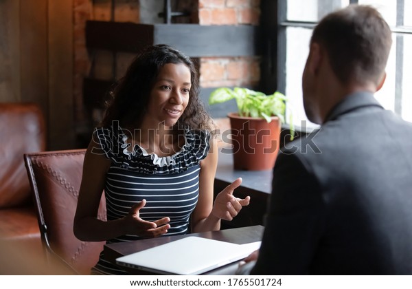 African applicant answer questions at job interview meeting in cafe with employer. Human resources, staffing process. Client and representatives communication, make offer sell company services concept