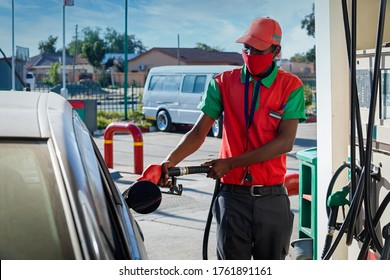 African attendant at a gas station handling a pipe nozzle refueling a car