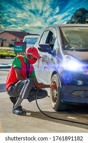 African Attendant At A Petrol Station Inflating The Tires Of A Small Budget Car