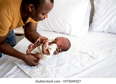 African Baby Black Skin Newborn Son Is 12-day-old, Lying On A White Bed And Is Crying, And African Father Was Holding Him, To Family And Baby Black Skin Newborn Concept.