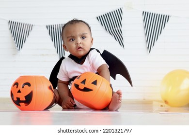 African Baby Kid Dressing Up In Vampire Fancy Halloween Costume With Black Bat Wings, Little Cute Child Go To Party, Playing Trick Or Treat, Holding Orang Pumpkin Basket. Happy Halloween Celebration.