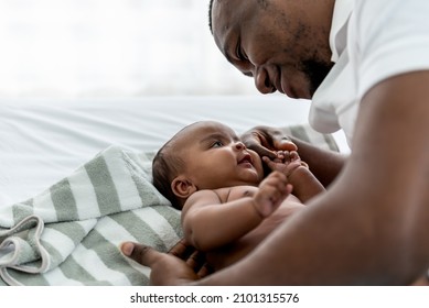 African Baby Newborn Daughter Is 3 Month Old Lying On White Bed And Father Are Looking Into Each Other's Eyes And Smiling With Happy, To Relationship African Family And Baby Newborn Concept.