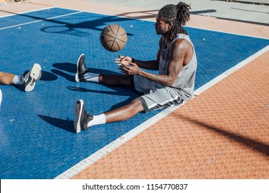 African basketball player sitting on court and doing exercise. - Powered by Shutterstock