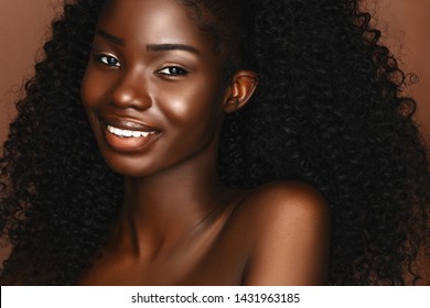 African beautiful woman portrait. Brunette curly haired young model with dark skin and perfect smile