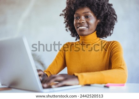 African black business woman working on laptop at office. African american businesswoman lookingup at copy space while working on phone. Successful woman entrepreneur think about new business ideas.
