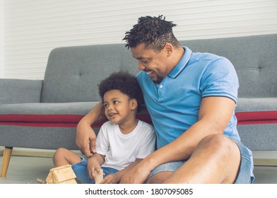 African Black Father Is Playing And Hug His Son In Living Room At Home. Education And Family Concept.