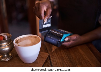 African Black Female Waitress Swiping A Credit Card Through A Mobile Card Machine For Cappuccino In Restaurant Randburg, Johannesburg, Gauteng South Africa