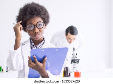 African black little boy wearing eyeglasses, studying science in classroom at school and thinking of something with blur background of teacher. Education concept. - Powered by Shutterstock