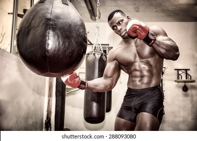 African black male boxer punching ball wearing boxing gloves in gym - Powered by Shutterstock