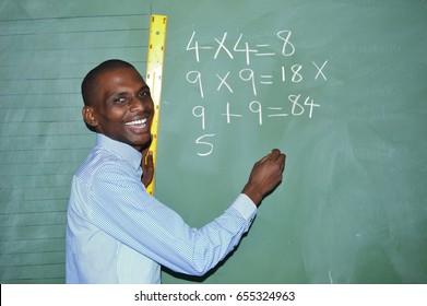 African black teacher with a big smile writing on board in class