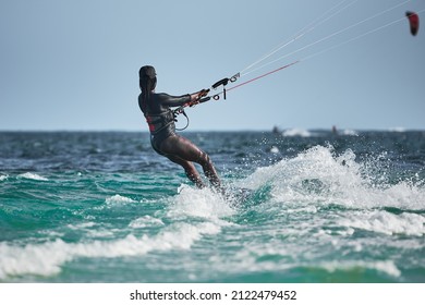 African Black Woman Kite Surfing Kit-surfing On The Tropical Green Sea Water. Kenyan Black Girl Kitesurfing On The Indian Ocean