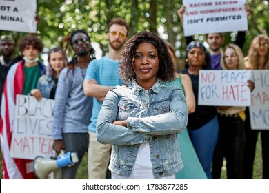 African Black Woman Leading A Group Of Demonstrators In The Park. Group Of People Protesting For Human Rights And Against Racism