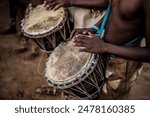 African Botswana youth playing drums made out of animal skin and wood.