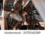 African Botswana youth playing drums made out of animal skin and wood.