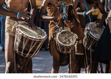 African Botswana youth playing drums made out of animal skin and wood.