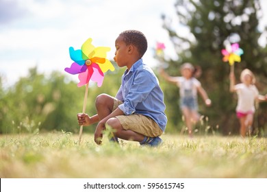 African boy and friends with pinwheels playing at the park - Powered by Shutterstock