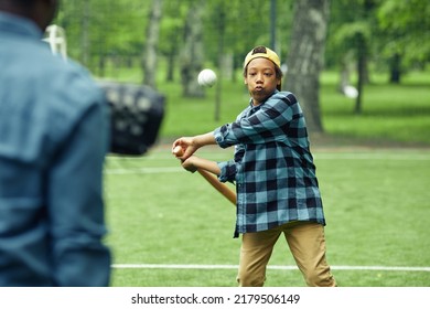 African Boy Learning To Hit The Ball With Bat During Game In Baseball Together With His Dad