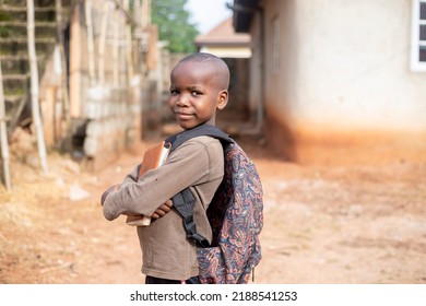 An African boy student wearing bag pack and holding book smiling and looking at camera - Powered by Shutterstock
