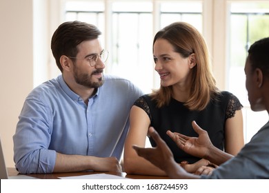 African broker convincing european couple customer buy company services, property during meeting in office. Spouses young family and agent negotiating, client and manager communication process concept