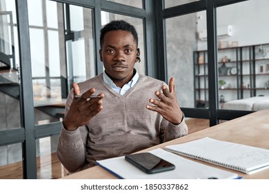 African business man, coach, executive wearing headset talking to camera conference video calling, giving webinar, online class, distance teaching or working at home office, web cam view. Headshot.