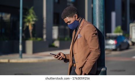 African Business Man With Face Mask Waiting At Street Corner With Mobile Phone