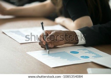 African businessman, business investor or customer analyzing benefits in project statistics document with rising increasing graphs, checking financial result in report paper at meeting, close up view