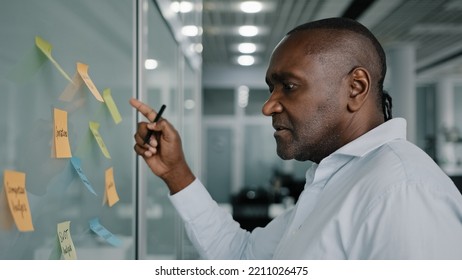 African Businessman Executive Content Manager Develop Strategy Plan Manage Corporate Work Tasks Read Sticky Notes Glued To Board Write Ideas Project Points On Memo Stickers Planning Goals Brainstorm