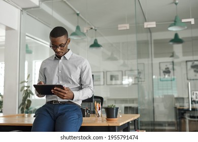 African Businessman Leaning On An Office Desk Using A Tablet