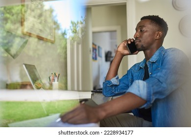 African businessman talking on a phone inside his home office - Shutterstock ID 2228934177